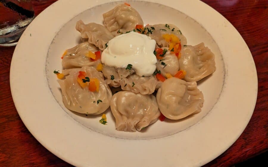 Pelmeni topped with sour cream and fresh herbs